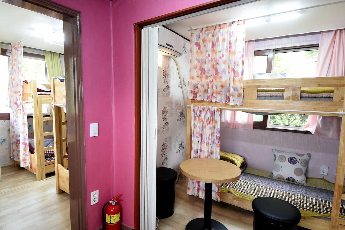 A compact room with bunk beds, a small round table, and a fire extinguisher.