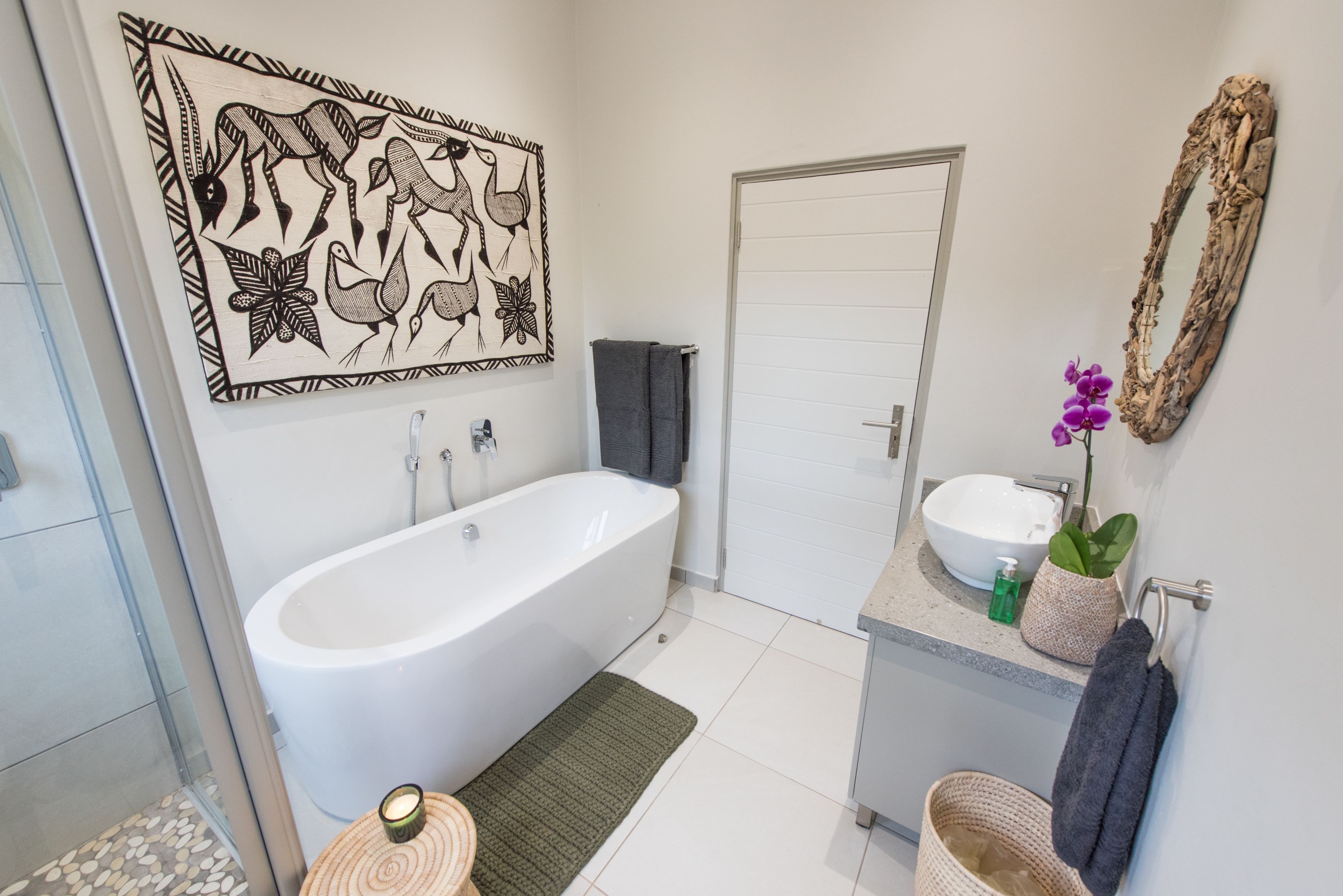 Une salle de bain moderne avec une baignoire sur pieds, un grand miroir et un élément décoratif mural.