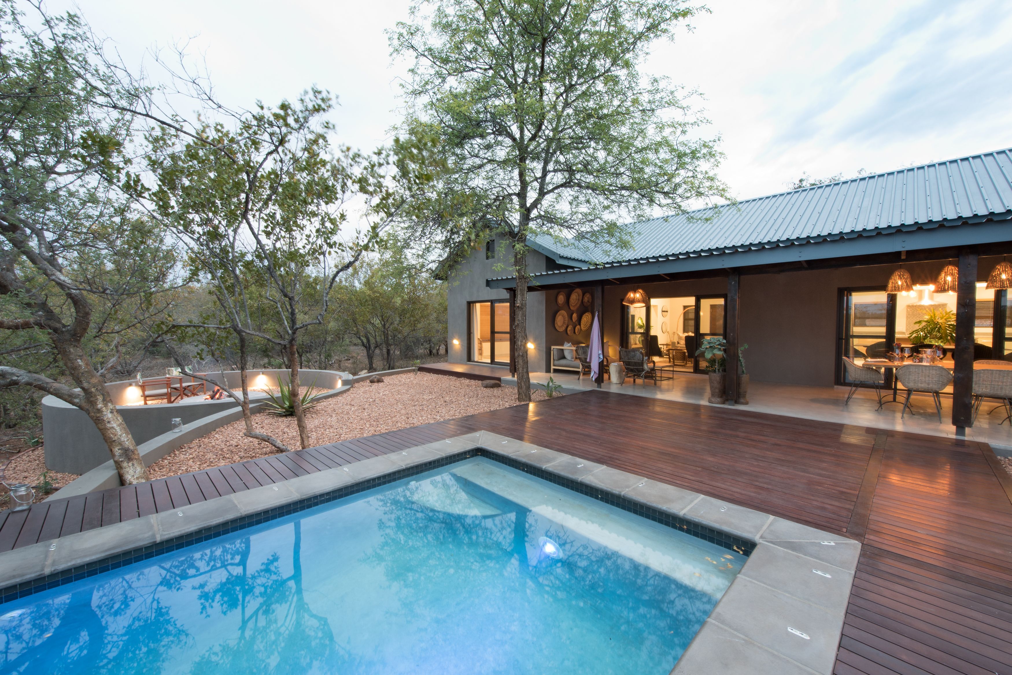 A modern house with a swimming pool, wooden deck, and outdoor seating area.
