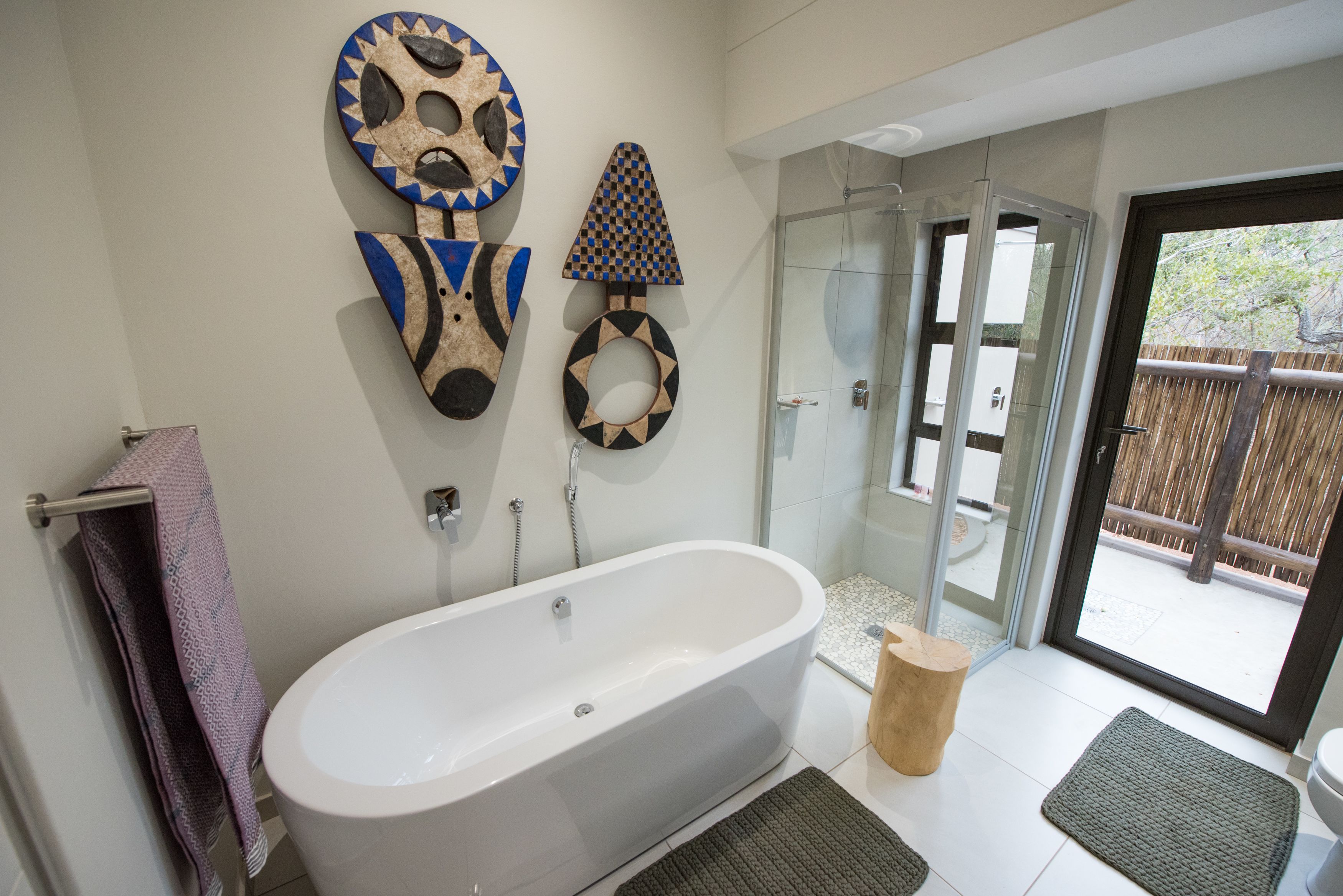 A modern bathroom with a freestanding bathtub, glass shower enclosure, and decorative wall art.