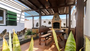 Une terrasse extérieure dotée d’une cheminée en pierre, de meubles en bois et offrant une vue sur les montagnes.