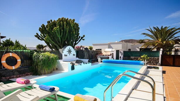 Une piscine avec des chaises longues, une bouée de sauvetage et un cactus.