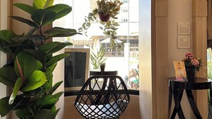 A modern interior with a glass partition, potted plants, a black chair, and a small table with a WiFi sign. - Bhundaree Richy (Hat Yai)