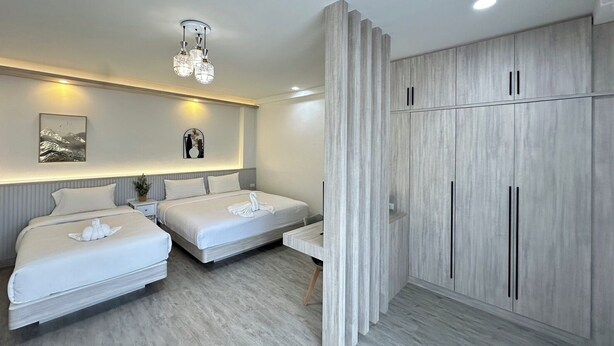 A modern hotel room with two beds, a large wardrobe, and a chandelier. - Bhundaree Richy (Hat Yai)