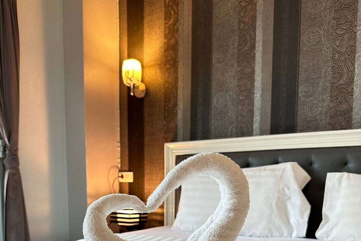 Una habitación de hotel con cama, mesita de noche y lámpara de pared.
