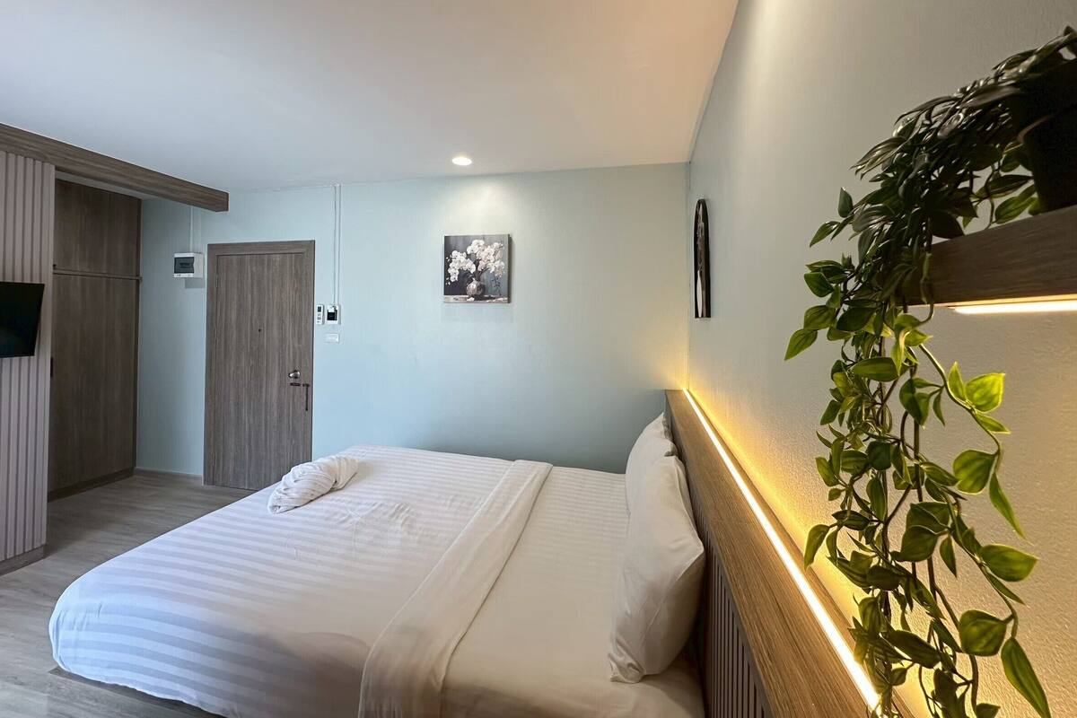 Un dormitorio moderno con una cama, un armario de madera, un televisor montado en la pared y un cuadro enmarcado.