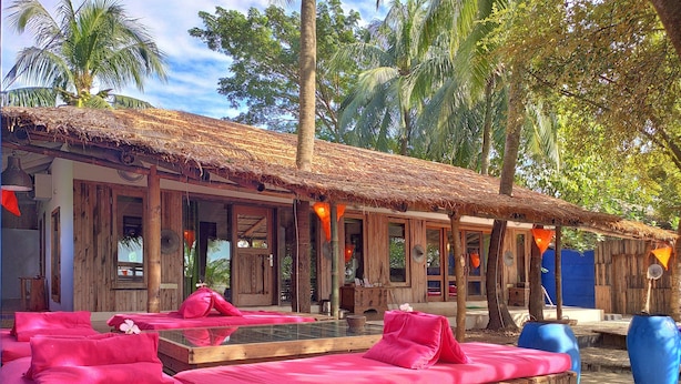 A wooden structure with thatched roofs, outdoor seating with pink cushions, and a pool area. - Mermaid Beach Resort (Cox's Bazar)