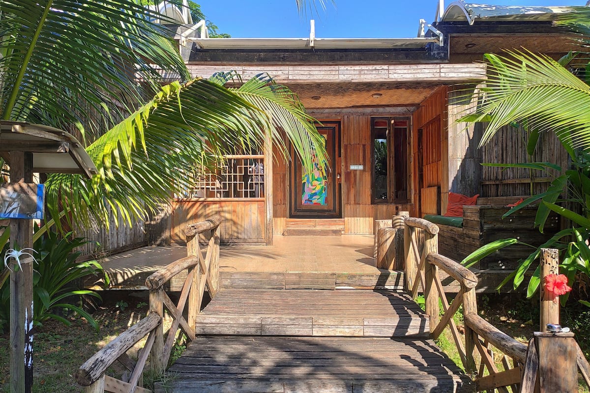 A wooden pathway leading to a rustic building with a wooden door and a colorful mural.