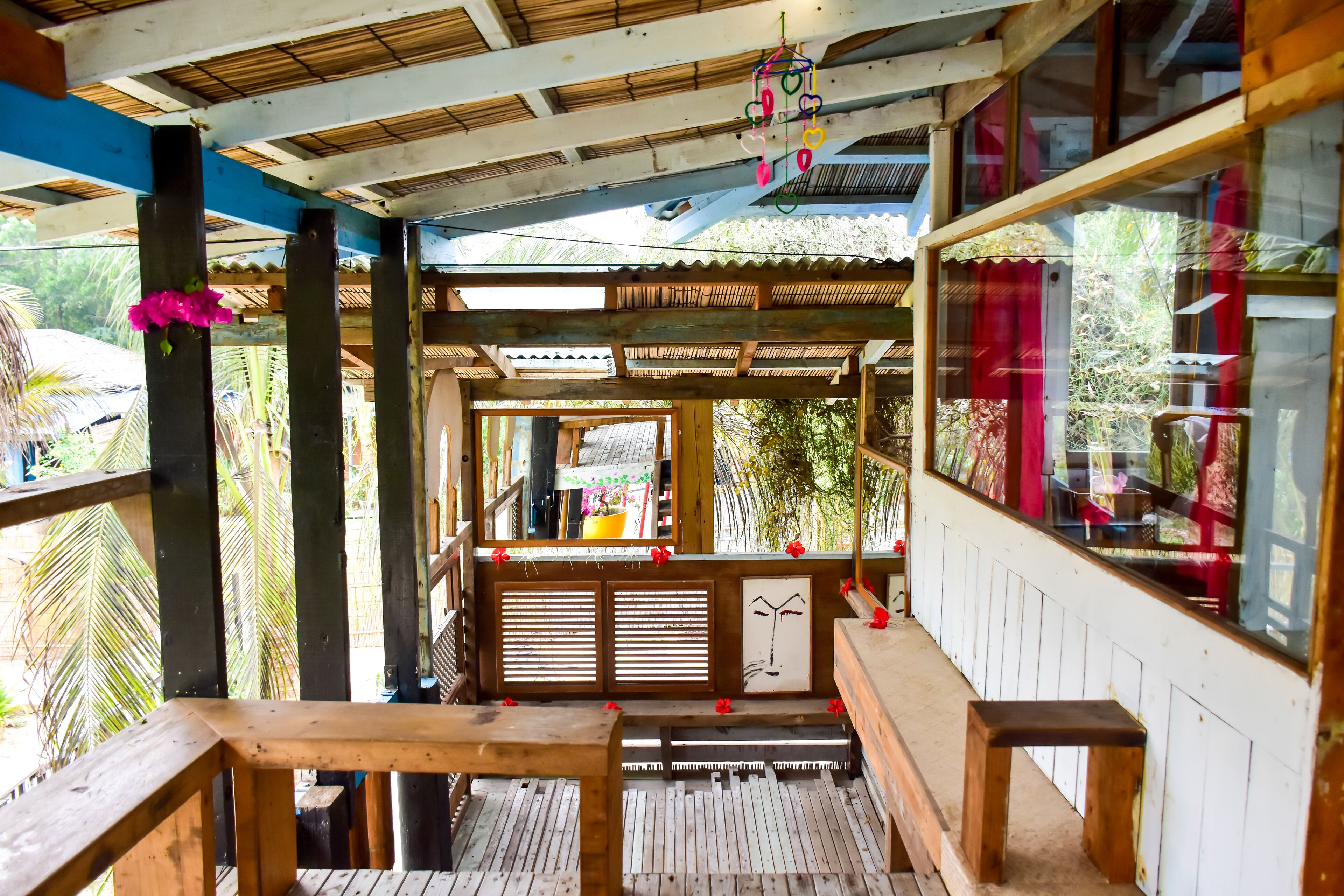 A wooden deck with benches and a railing, overlooking a garden area with palm trees.