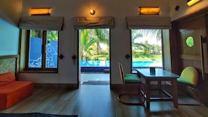 A room with a wooden ceiling, a pool view, a dining table, and a sofa. - Mermaid Beach Resort (Cox's Bazar)