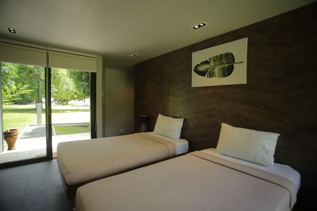 A hotel room with two beds, a large window, and a wall-mounted artwork.