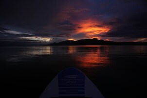 A surfboard with the text "Pathfinder P73" against a sunset over water.