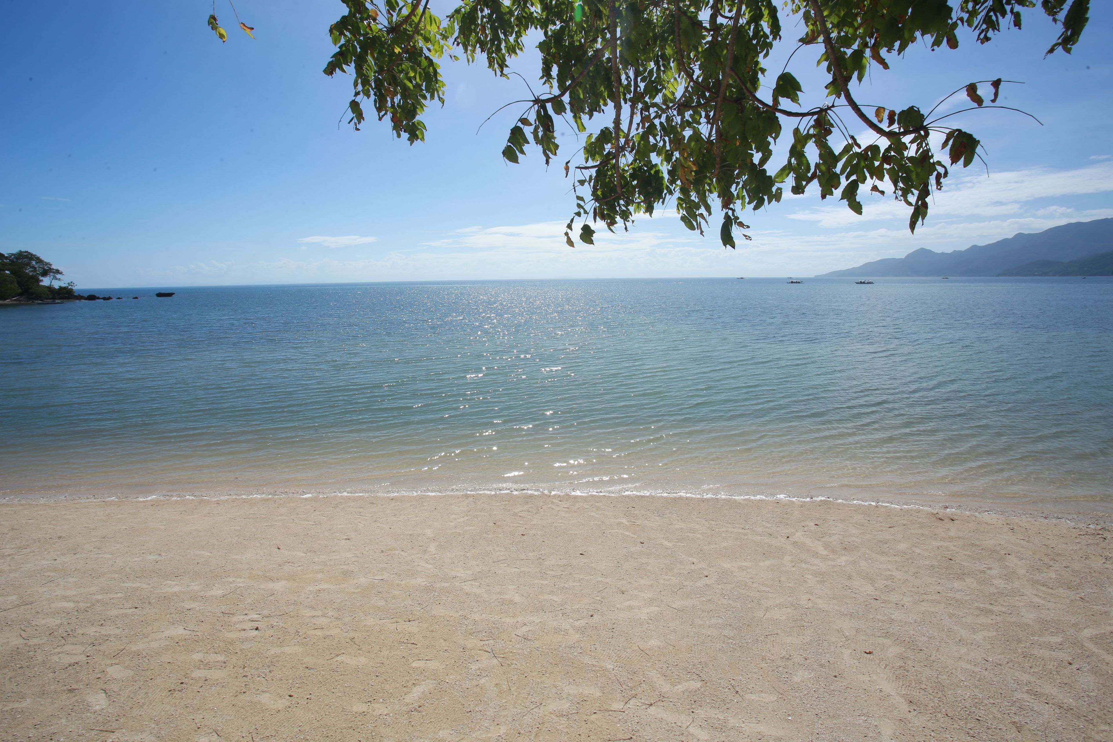 A beach with clear water and a sandy shore.