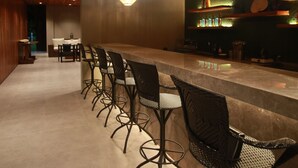 A bar area with a long counter, black mesh chairs, and hanging wicker pendant lights. - Cala Laiya (San Juan)