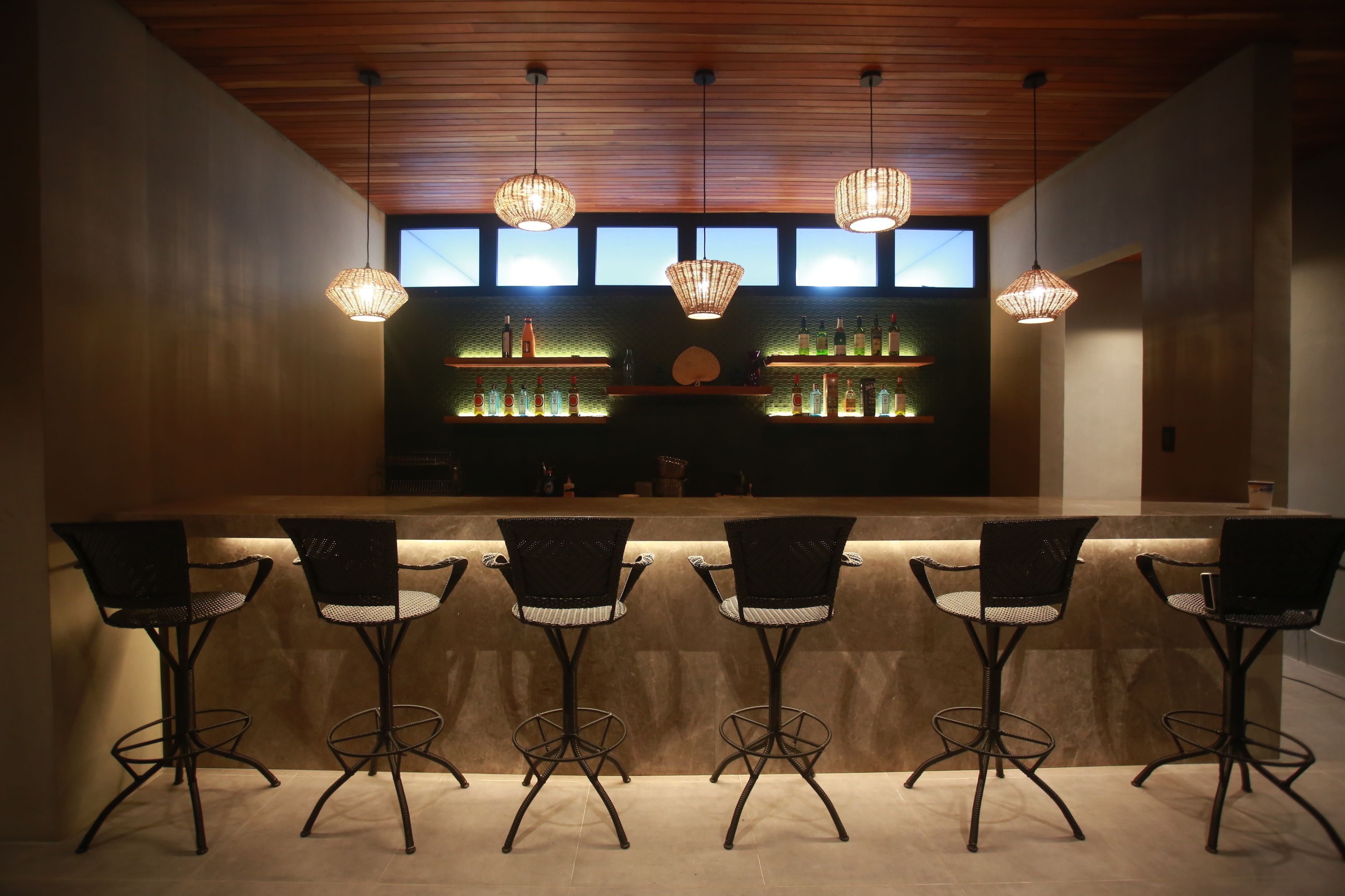 A bar area with a counter, five chairs, and hanging lights.