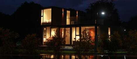 Una casa moderna con amplios ventanales y su reflejo en el agua.