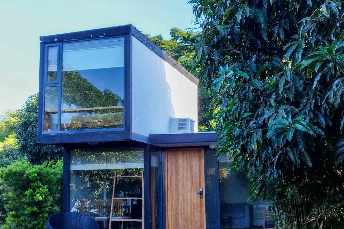 A modern two-story house with large glass windows, a wooden door, and a concrete exterior.