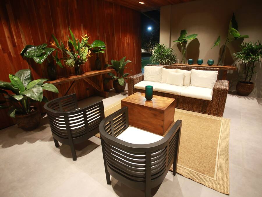 Un rincón acogedor con un sofá, dos sillones, una mesa de centro y varias plantas en macetas.