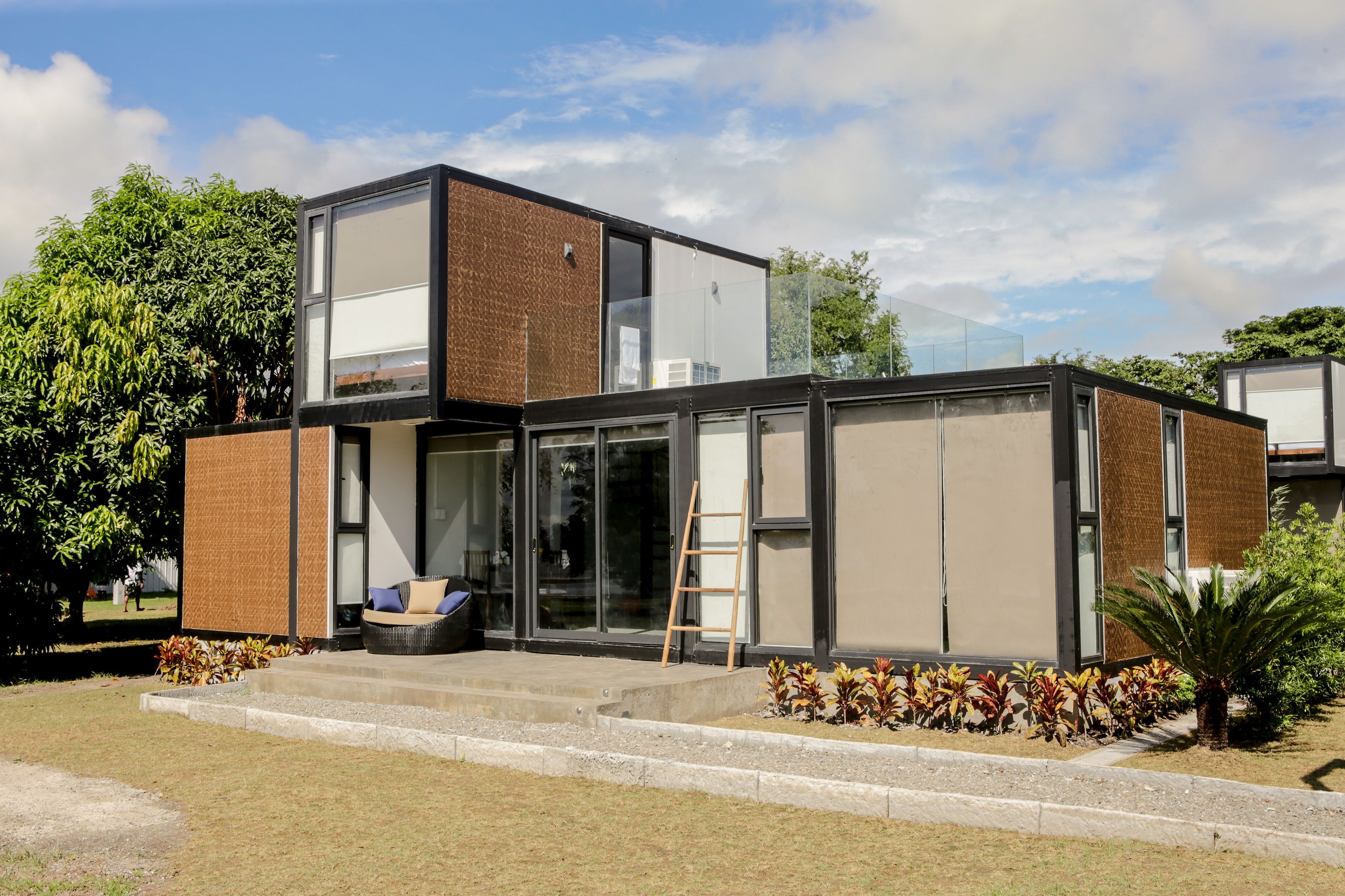 En moderne bygning med en glasfacade, en trætrap og et lille siddeområde med hynder.
