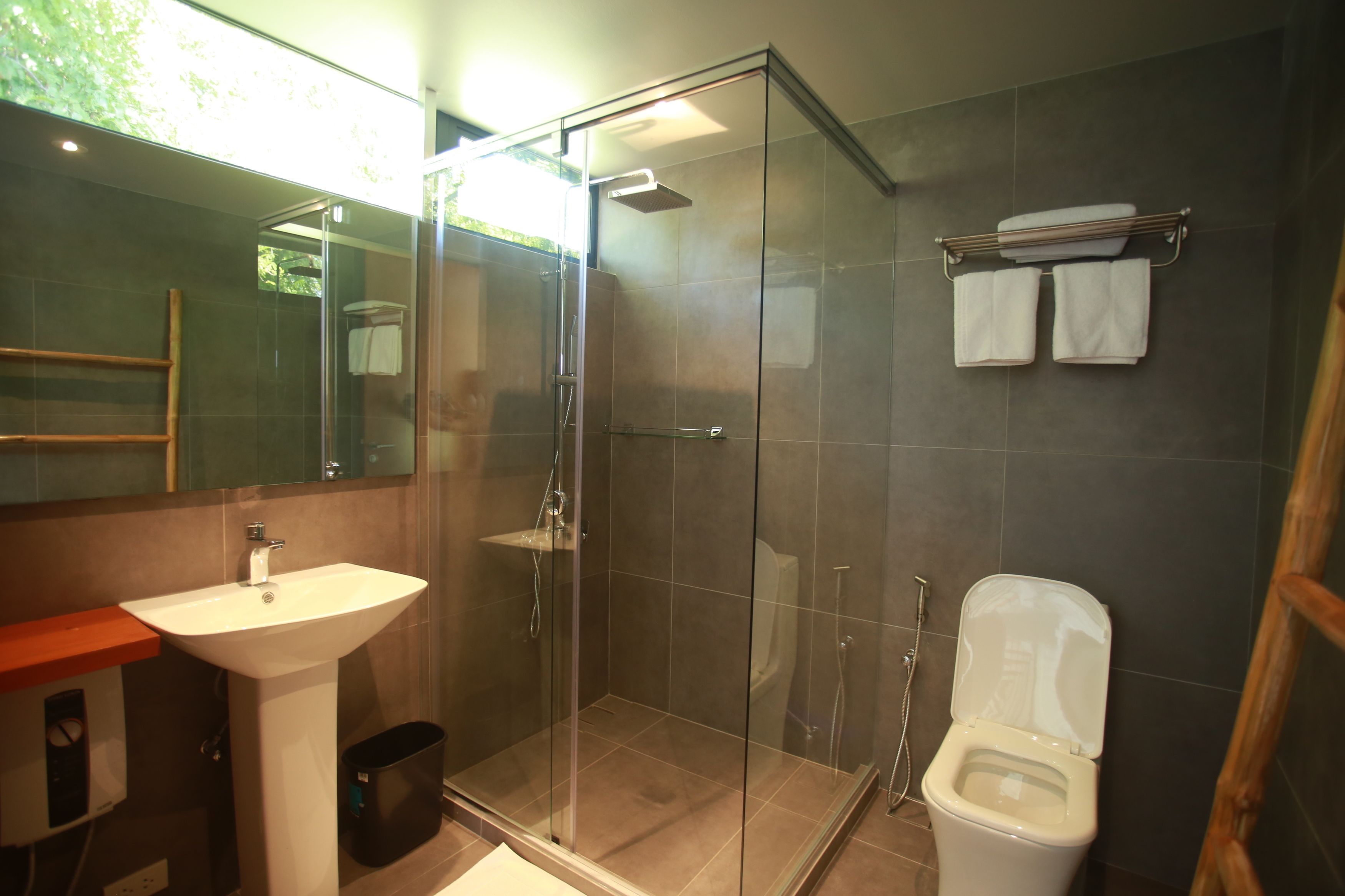 Ein modernes Badezimmer mit einer Duschkabine, einem weißen Waschbecken und einer Toilette.