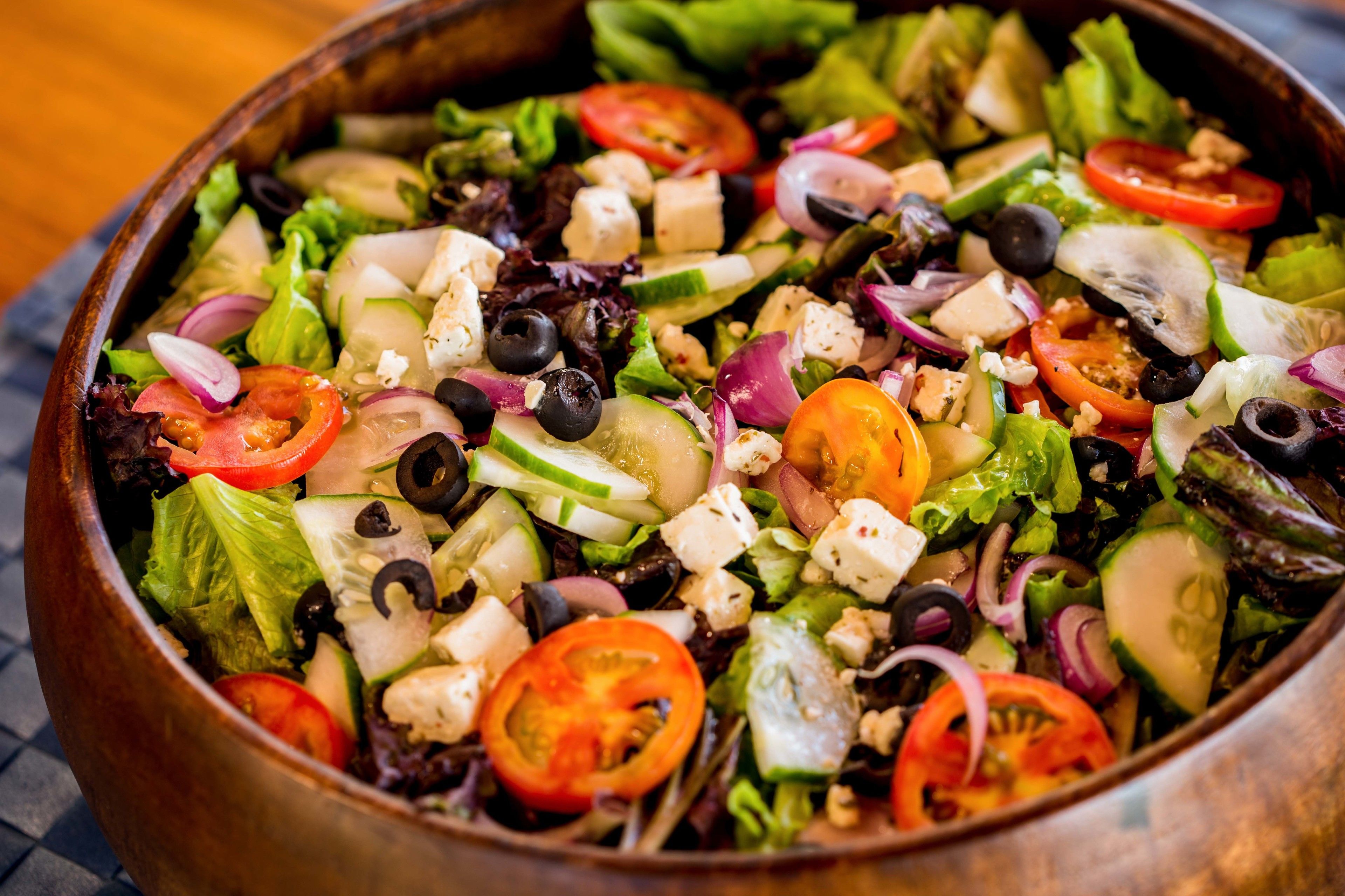 A bowl of salad with various vegetables and cheese.