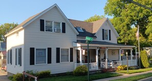 Une maison à deux étages avec un porche à l’avant, un garage et un panneau de signalisation indiquant le croisement des rues Second et Walton.