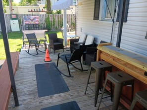 Un espace extérieur aménagé en terrasse, avec une plateforme en bois, du mobilier d’extérieur et une petite table.