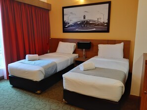 A hotel room with two beds, a nightstand, a lamp, and a framed picture on the wall. - Hotel Scholar's Suites (Tanjung Malim)