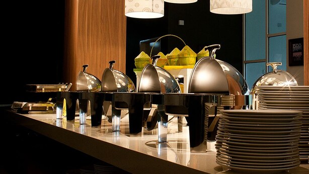 A buffet setup with multiple food service stations, including covered serving dishes and stacked plates.