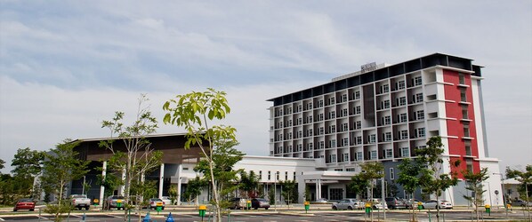 A modern hotel with a multi-story structure, a covered entrance, and a parking area with several cars. - Hotel Scholar's Suites (Tanjung Malim)