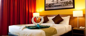A hotel room with a bed, red curtains, a framed picture on the wall, and two bedside lamps. - Hotel Scholar's Suites (Tanjung Malim)