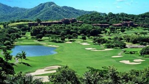 A golf course with a lake, surrounded by lush greenery and hills. - Luxury Oceanview Penthouse -
Private Beach Club Access -
Reserva Conchal (Brasilito)