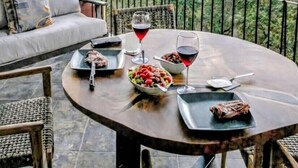 A dining table with food and drinks, a sofa, and a view of a mountainous landscape. - Luxury Oceanview Penthouse -
Private Beach Club Access -
Reserva Conchal (Brasilito)
