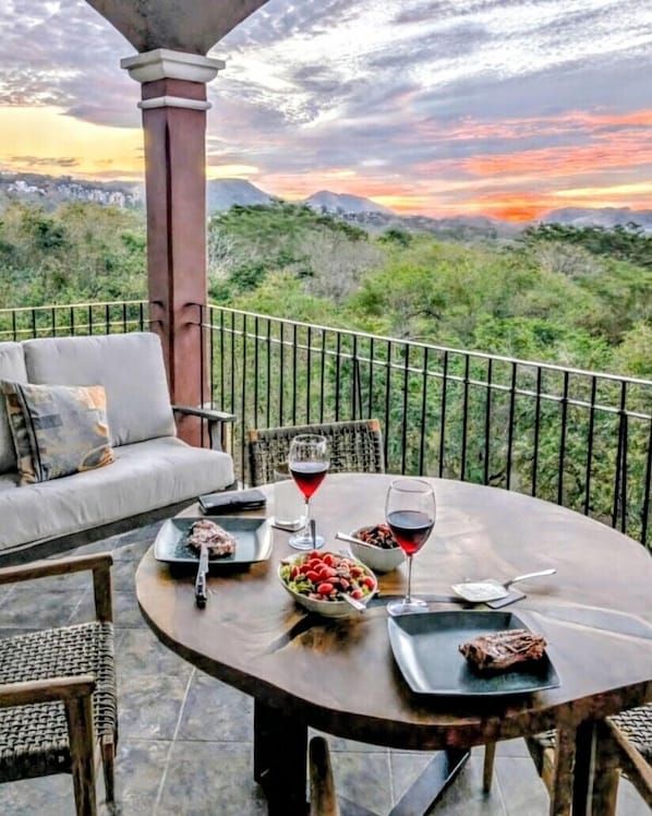 Une table à manger avec de la nourriture et des boissons, un canapé et une vue sur un paysage montagneux.