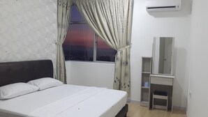 Un dormitorio con cama, una ventana con cortinas, un escritorio y un equipo de aire acondicionado.