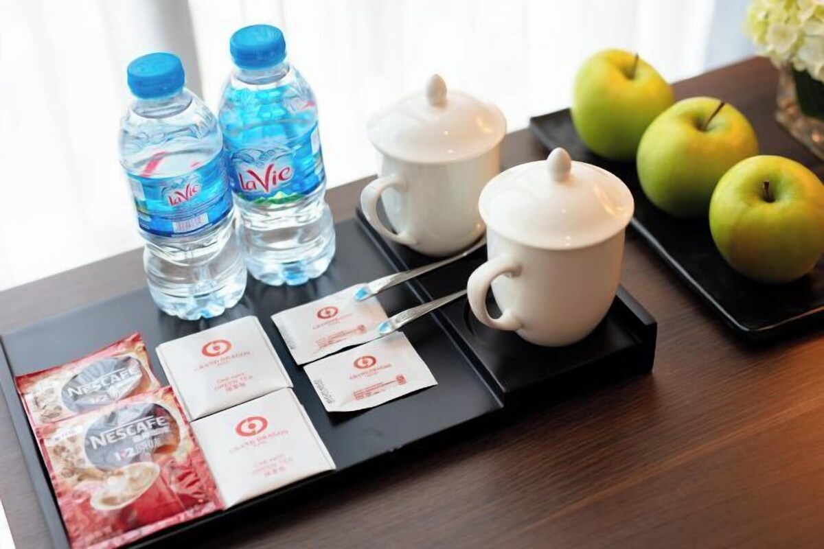A tray with water bottles, coffee cups, and a plate of apples.