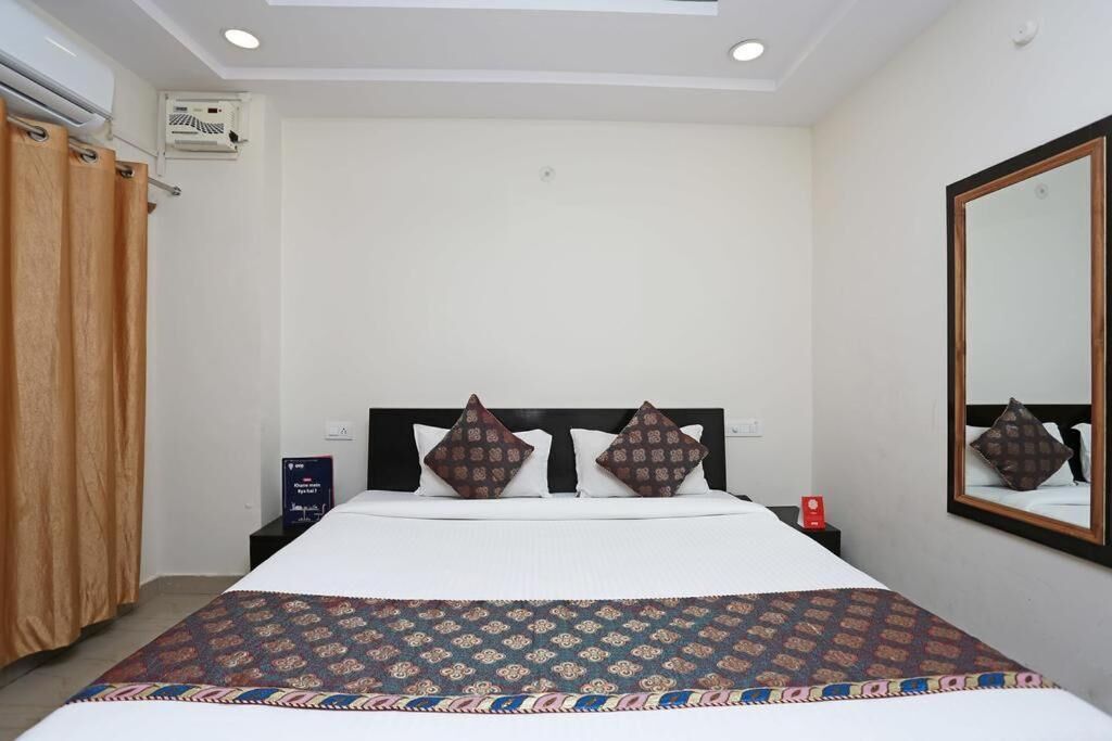 Una habitación de hotel con cama, mesita de noche, espejo y ventilador de techo.