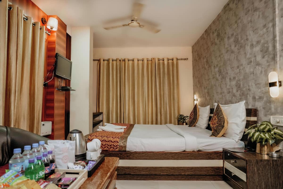 A hotel room with a bed, a desk with toiletries, a TV, and a ceiling fan.