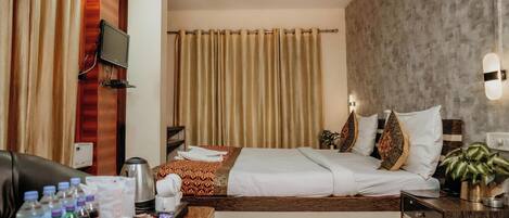 A hotel room with a bed, a desk with toiletries, a TV, and a ceiling fan.