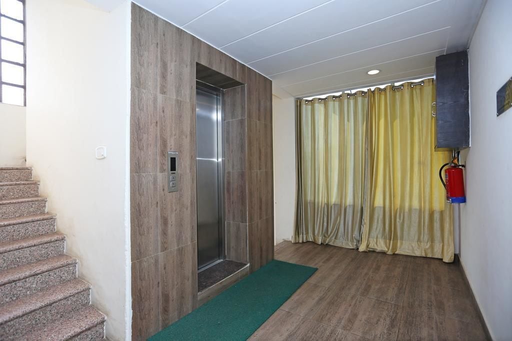 A hallway with a staircase, a vertical elevator, and a yellow curtain.