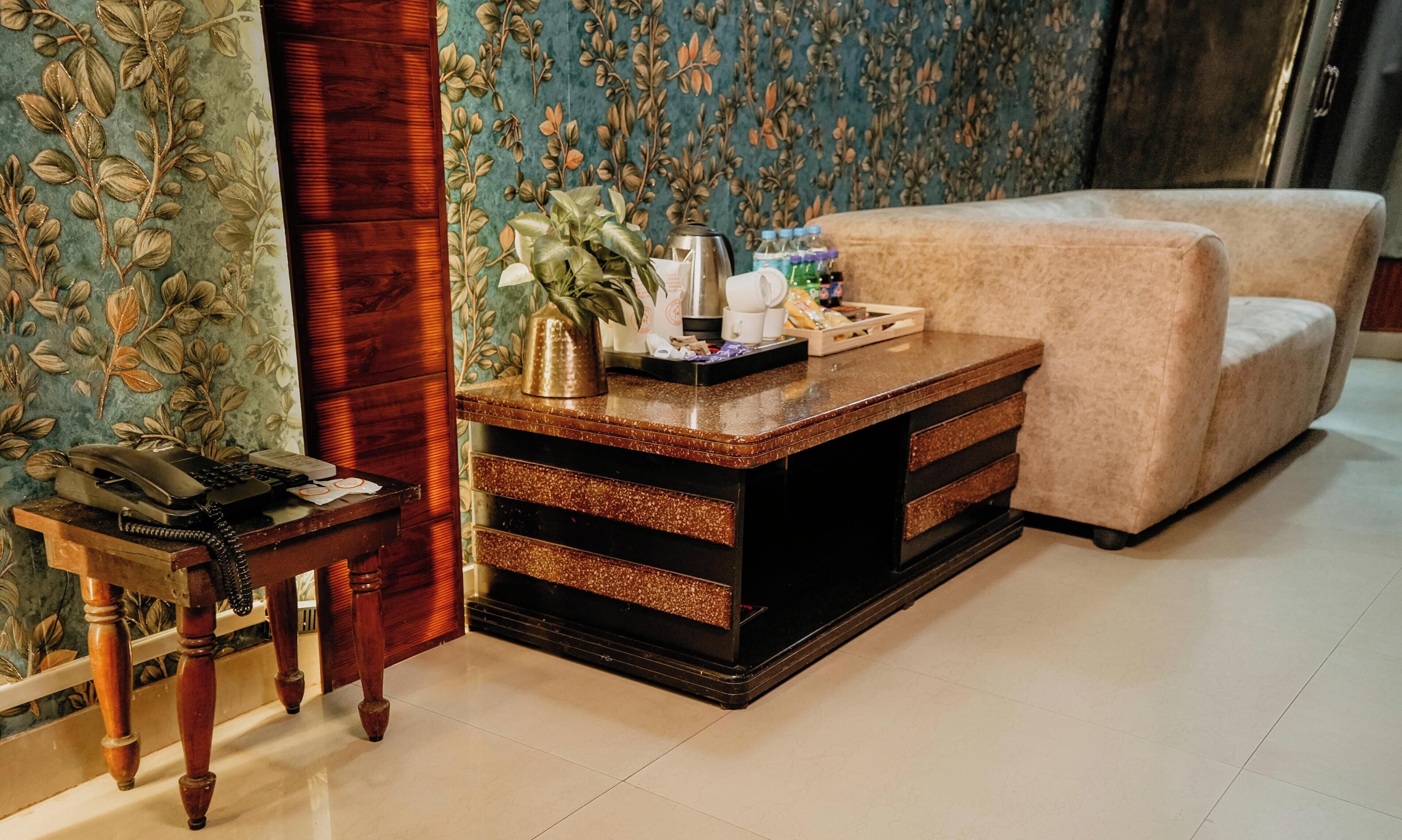 A room with a wooden desk, a telephone, a coffee maker, and a sofa.