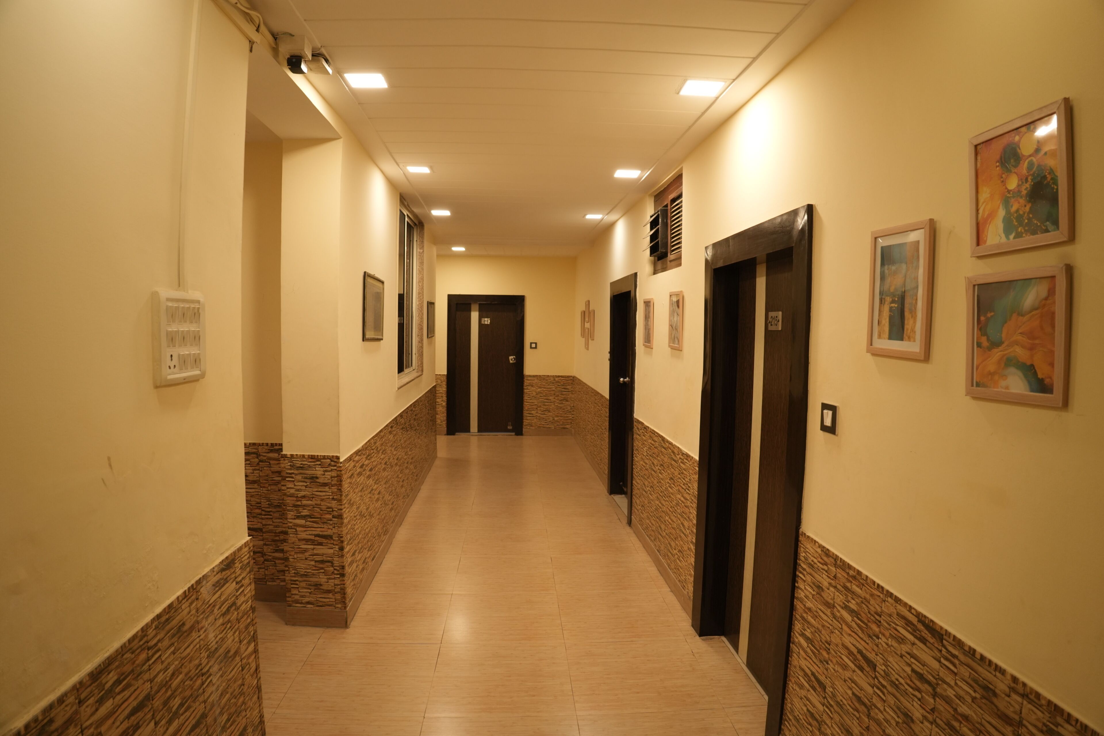 A hallway with a tiled floor, doors, and framed artwork on the walls.