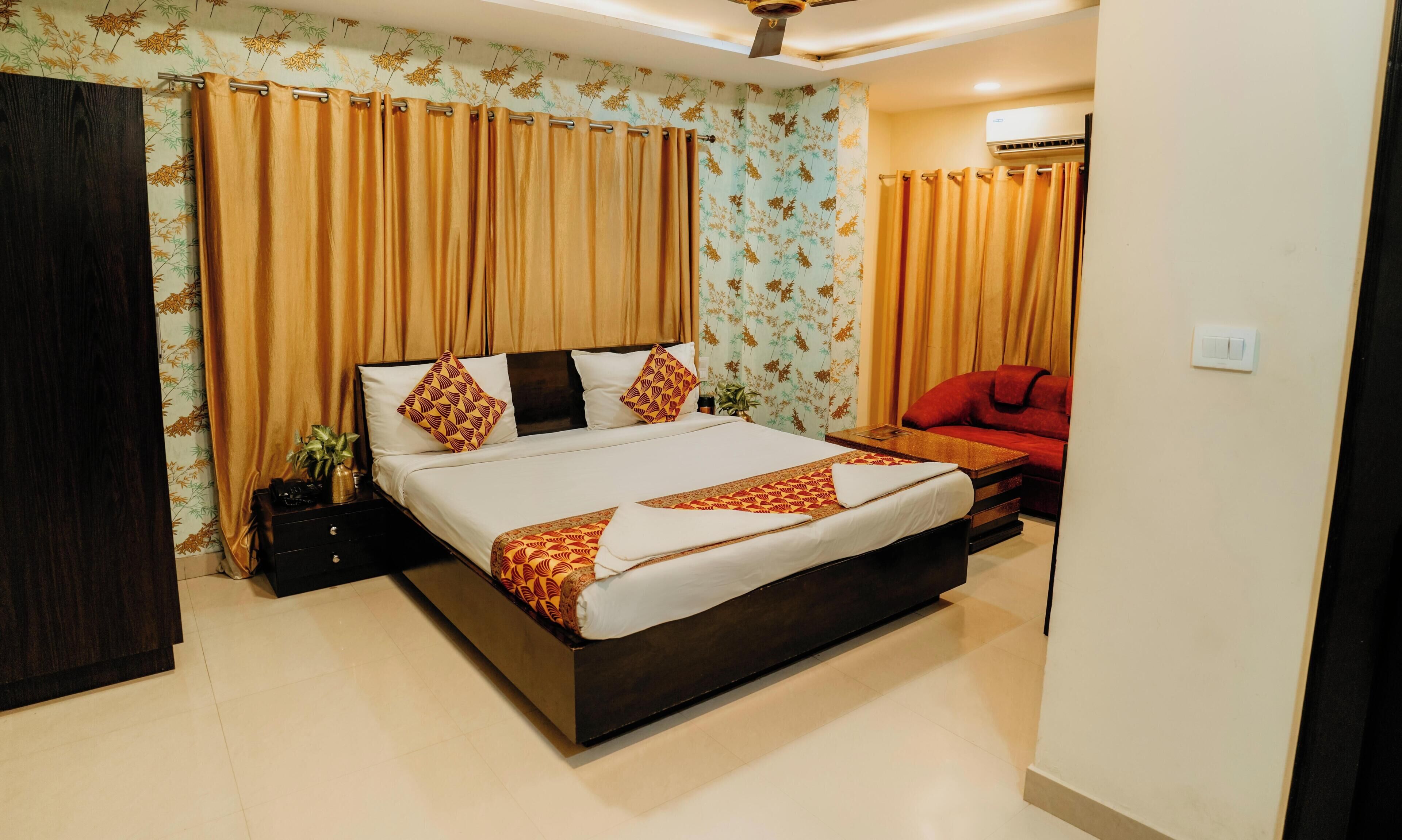 Une chambre d’hôtel avec un grand lit, un canapé rouge et un ventilateur de plafond.