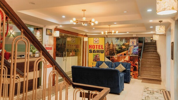 A hotel lobby with a staircase, a sofa, a chandelier, and a wall with a 'HOTEL SAHU' sign. - Hotel Sahu Near Kashi Vishwanath Temple Gate (Varanasi)
