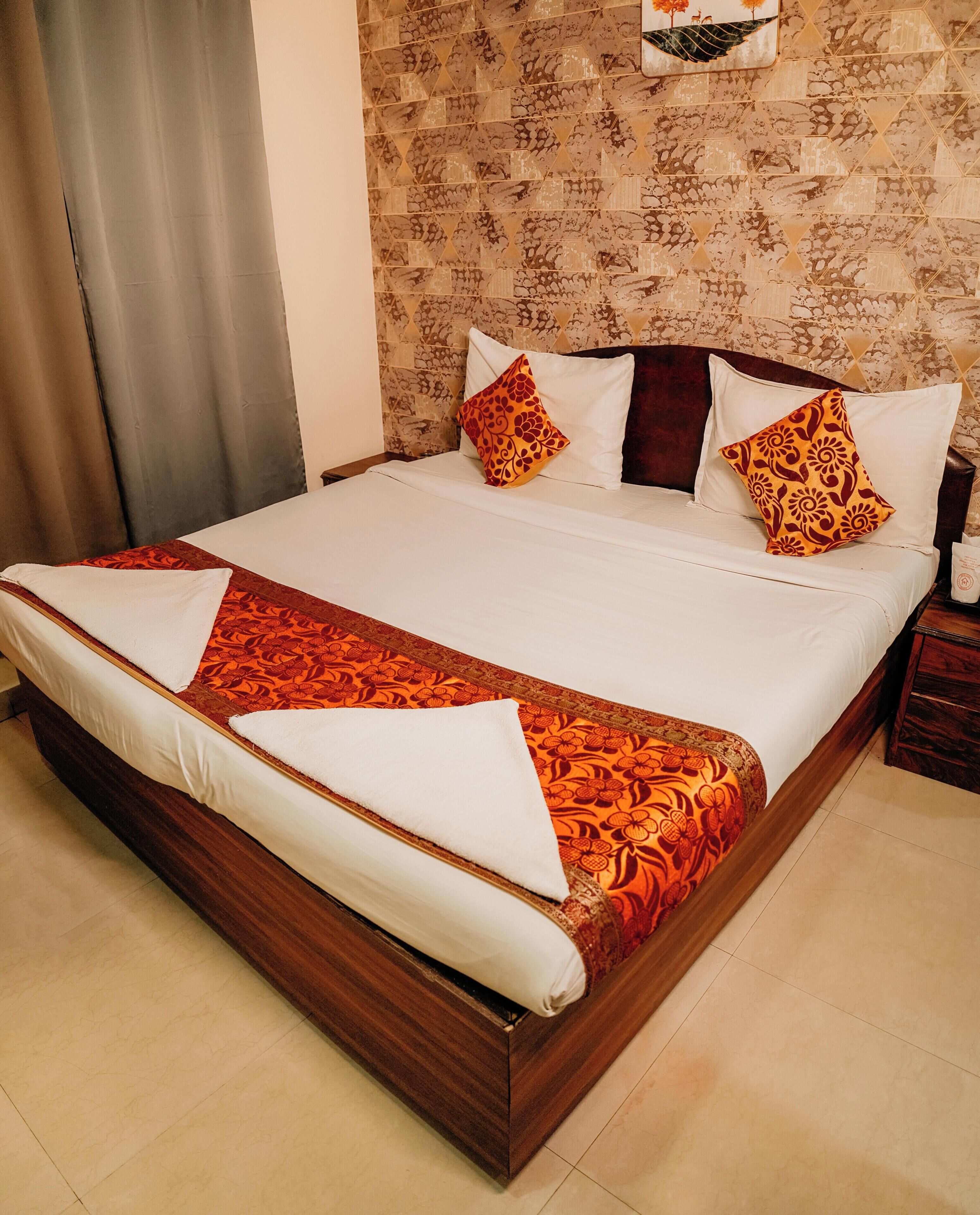 Ein ordentlich gemachtes Bett mit einem gemusterten Bettüberwurf, zwei Kissen mit floralen Mustern und einem Holz-Kopfschild.