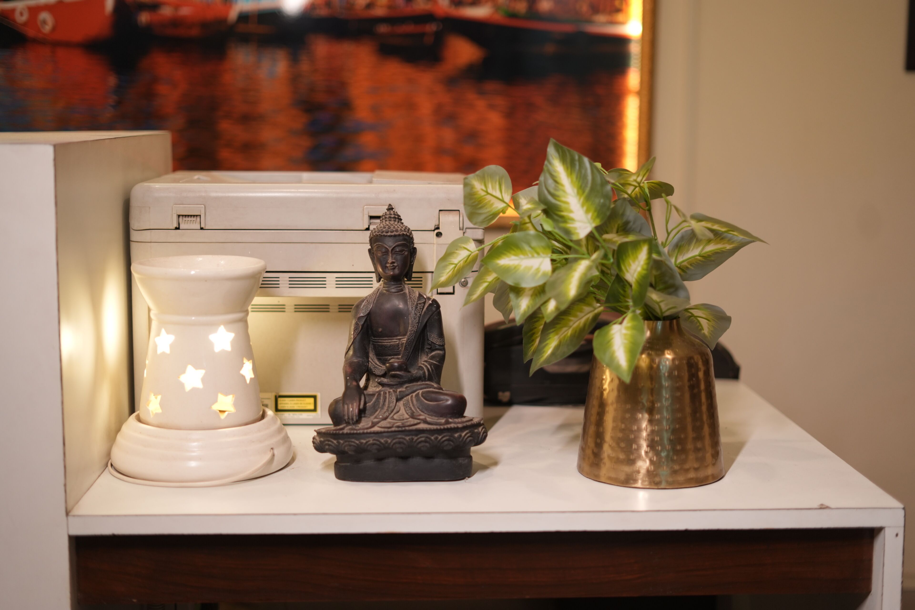 A Buddha statue, a star-shaped lamp, and a potted plant on a shelf.