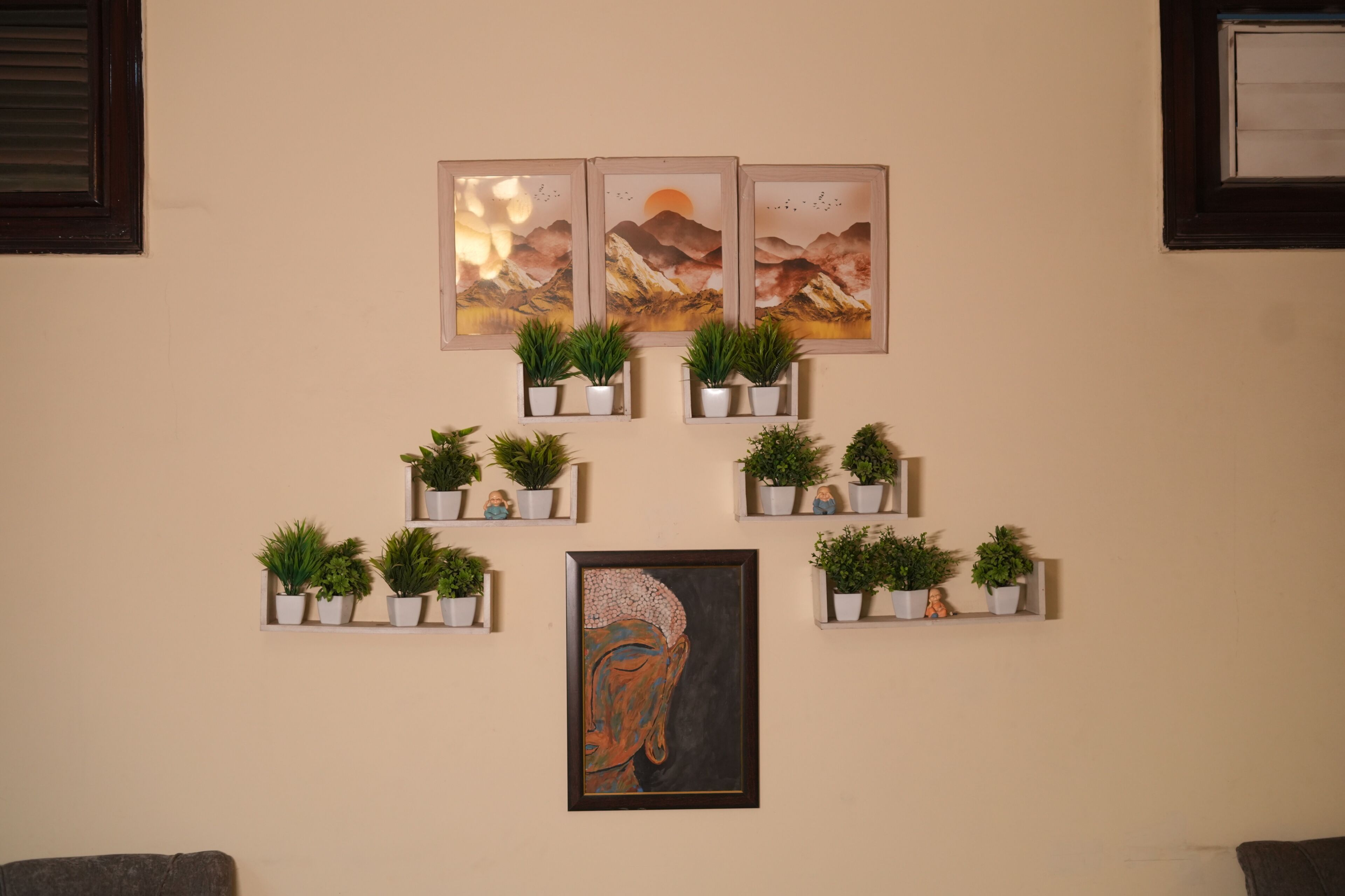 A wall with framed artwork and potted plants arranged in shelves.