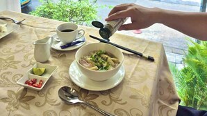 Une table avec un bol de soupe, une tasse, des baguettes, une cuillère et une petite assiette contenant des piments.