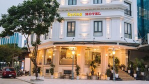 Un hôtel à la façade classique, doté d’une entrée imposante et d’une terrasse.