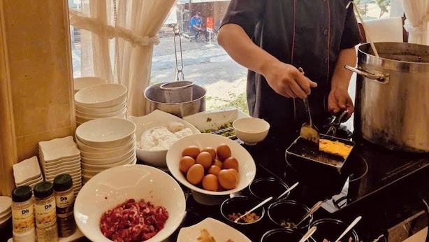 Un stand de nourriture installé au bord de la rue, où un chef prépare des plats, avec divers ustensiles de cuisine et des ingrédients visibles.